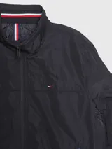 Campera bomber Tommy Hilfiger negra de poliéster, con cuello alto, cierre frontal con cremallera, dos bolsillos laterales con cremallera, puños elásticos y logo bordado en el pecho.