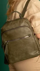 Mochila urbana color verde militar de símil cuero, con dos bolsillos frontales, bolsillo principal de gran capacidad, dos bolsillos internos con cierre y uno abierto, bolsillos laterales abiertos, asa de mano y correas regulables en galón.
