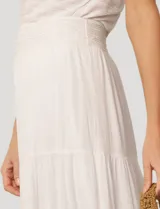 Falda larga de crepé de rayón color blanco, con diseño de paneles escalonados y detalles de puntilla. Presenta una silueta holgada y cintura elástica.