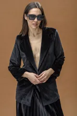 Blazer de terciopelo negro con solapas clásicas, cierre frontal con un botón y bolsillos laterales con solapa.