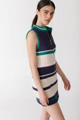 Vestido corto tejido de punto a rayas horizontales en tonos celeste, crema, marrón y mostaza. Tiene cuello alto y cierre metálico frontal. Sin mangas.