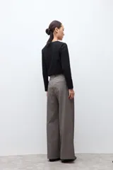 Pantalón sastrero de corte recto y tiro alto, confeccionado en tela con textura melange en tono beige. Presenta cierre frontal con botón y bolsillos laterales.