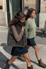 Chaleco de pelo sintético color verde oscuro, con cuello alto y sin mangas. Cierre frontal con ganchos metálicos forrados.