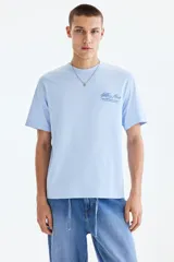 Remera celeste de corte holgado, con cuello redondo y diseño estampado en el pecho.