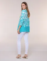 Blusa azul y blanca con estampado floral y geométrico, de calce suelto, con escote redondo, abertura tipo keyhole en el pecho, mangas tres cuartos y ruedo amplio con silueta evasé.