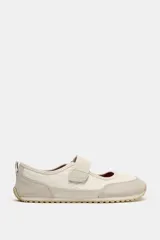 Bailarina deportiva tipo barefoot en color beige, con puntera amplia, cierre de velcro en el empeine, detalles en gamuza y suela flexible de goma.