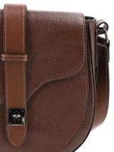 Bandolera de cuero graneado color marrón chocolate, de formato rígido y diseño con estética setentosa. Cuenta con solapa frontal con detalle de tira vertical y herraje metálico de cierre, y correa ajustable para colgar al hombro o cruzada.