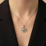 Dije circular de plata 925 con números romanos grabados en el borde y centro en oro, con diseño inspirado en un reloj.