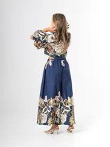 Conjunto de dos piezas confeccionado en viscosa con estampado floral en tonos marrones y verdes sobre base blanca. Incluye una blusa tipo camisa corta con cuello solapa, cierre frontal de botones y mangas abullonadas con diseño globo, y un pantalón tipo culotte de tiro alto, amplio y fluido con pinzas en la cintura.