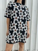 Vestido corto negro con estampado de flores blancas y marrones, de corte holgado y manga corta.