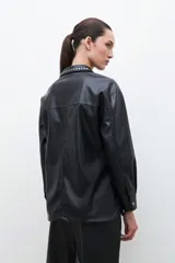 Sobrecamisa negra de cuero sintético con cuello camisero y tachas plateadas.