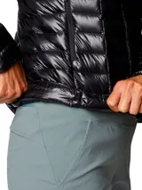 Campera puffer ultraligera de color negro con capucha, marca Mountain Hardwear modelo Ghost Whisperer. Presenta tejido ripstop, aislamiento de plumón, cierre frontal completo y bolsillos laterales con cremallera.