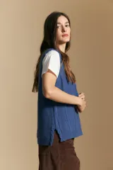 Chaleco tejido color azul, con escote en V, cierre frontal con botones y diseño de líneas verticales en relieve. Presenta terminaciones acanaladas en el ruedo y un borde ondulado en el escote.