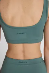 Top deportivo verde con doble escote superpuesto, confeccionado en textil Activelu con compresión media, protección UV50+ y nula transparencia.