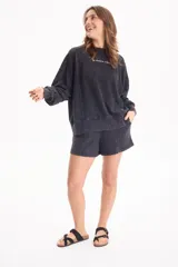 Buzo deportivo sin frisa de color negro con efecto lavado, cuello redondo, mangas largas y estampa frontal con texto en blanco.