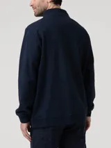 Buzo de tejido de punto color azul marino jaspeado, con cuello alto y cierre frontal parcial. Presenta un pequeño logo bordado en el pecho.