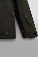 Cazadora deportiva de esquí con diseño bicolor en tonos negro y verde oliva. Presenta capucha amplia con visera, cierre frontal con cremallera termosellada, bolsillos frontales y en manga con cierres impermeables, y aberturas de ventilación en las axilas. Incluye faldón interior antinieve, puños ajustables y tecnología de rescate RECCO.