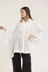 Camisa de manga ancha, color verde salvia, con cuello camisero y cierre frontal de botones. Presenta detalles de pespunte decorativo en el canesú frontal.