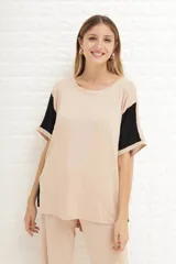 Remerón de manga corta, color beige claro, con bloques de color negro en las mangas. Presenta cuello redondo y un calce holgado.