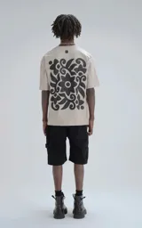 Remera de algodón color arena con estampado floral abstracto en color negro en la parte posterior y pequeño logo en la nuca.