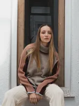 Buzo tejido de punto color crema con cuello alto y mangas largas con rayas horizontales en verde y lila.