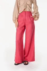 Pantalón de lino blanco de corte ancho y fluido, con cintura alta que incorpora una sobrepretina ancha desmontable con pliegues horizontales.