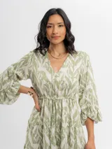 Vestido midi verde y crudo con estampado geométrico, escote en V con botones frontales, mangas tres cuartos acampanadas y falda con volados en capas.