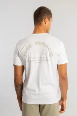Camiseta blanca de manga corta con estampado gráfico en la espalda que incluye texto y siluetas de aves.
