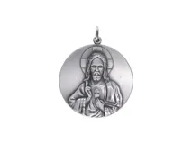 Dije redondo plateado con la imagen en relieve del Sagrado Corazón de Jesús.