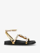 Sandalias planas doradas con tiras finas adornadas con cristales grandes y pequeños.