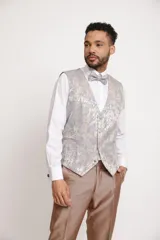 Traje de tres piezas color bronce con acabado satinado, compuesto por saco entallado, pantalón de vestir y chaleco con solapas estampadas en tonos grisáceos. Incluye moño a juego.