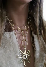 Collar con cadena de eslabones dorados y dije colgante en forma de flor con centro de cristal.