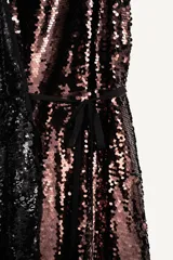 Vestido largo de lentejuelas con cuello halter, espalda descubierta y lazos para atar al cuello. Cuenta con un cinturón de lazo en contraste y diseño bicolor que combina tonos tostados y negros.