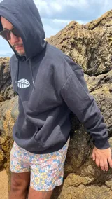 Hoodie negro con cordones ajustables y estampado de una hoja blanca en el frente.