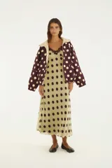 Vestido lencero midi de color verde claro con estampado de lunares marrón oscuro, tirantes finos y detalle de encaje marrón en el escote.
