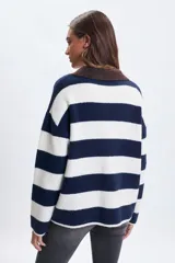 Sweater de punto con diseño de franjas horizontales anchas en azul marino y blanco. Presenta un cuello tipo polo en color bordó con escote en V y mangas largas de corte holgado.