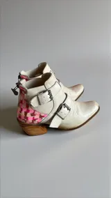 Botas de cuero natural color blanco marfil con diseño artístico pintado a mano en la parte trasera en tonos rosados y marrones, taco de madera y hebillas metálicas laterales.