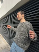 Sweater tejido a mano en lana color gris jaspeado, de calce holgado, con cuello a la base y puños ajustados.