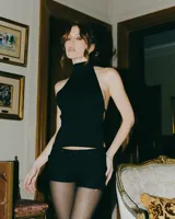 Top negro con cuello alto, espalda descubierta y corte ajustado.