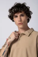 Chomba de manga corta con cuello polo, confeccionada en tejido de punto acanalado de textura pesada. Presenta un calce relajado y cuenta con una pequeña etiqueta distintiva en el ruedo.