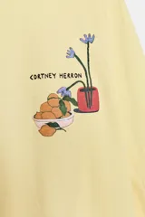 Camiseta de manga larga ranglán y cuello redondo, color amarillo, con estampado frontal a contraste.