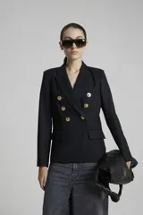 Saco negro de lana con calce entallado, cruzado con botones dorados con pie en delantero y bolsillos sastreros en delantero con tapa.