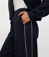 Pantalón wide leg de tiro medio, color azul marino con estampado de rayas diplomáticas blancas y detalle de piping lateral. Cuenta con cintura elástica y caída fluida.