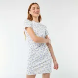 Vestido corto blanco con delicado estampado de pequeñas flores azules, de manga corta y cuello redondo. Presenta un diseño ajustado con un nudo decorativo fruncido en el lateral de la cintura.