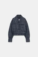 Cazadora corta de denim con efecto lavado, cuello solapa amplio, manga larga y cierre frontal cruzado con botones a presión. Presenta bolsillos laterales de vivo.