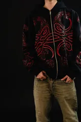 Hoodie con cierre frontal completo, confeccionado en algodón de tejido grueso. Presenta un diseño estampado en serigrafía con motivos de hojas de acanto en color rojo sobre fondo negro. Cuenta con bolsillos laterales y cierre metálico YKK.