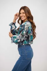 Camisa de manga larga con estampado floral en tonos azul, turquesa y blanco. Presenta cuello en V, cierre frontal con botones y puños elásticos con volados.