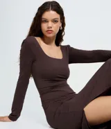 Vestido midi de microfibra color marrón, con escote cuadrado, manga larga y corte ajustado al cuerpo. Presenta una abertura lateral en la falda.