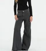 Jean de corte flare y tiro medio, confeccionado en denim negro con costuras verticales decorativas y ruedo deshilachado.