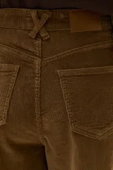 Pantalón de pana de corte recto y pierna ancha, color camel, con bolsillos frontales y costuras verticales decorativas en el frente.